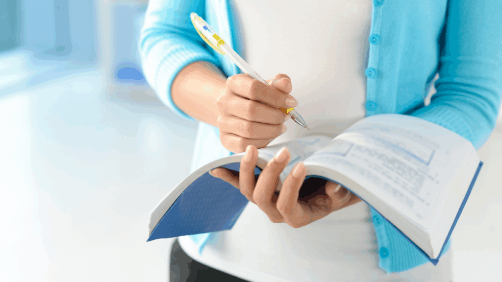 Frau schreibt mit einem Stift in ein geöffnetes Notizbuch – Symbol für Planung, Struktur und kontinuierliches Lernen.